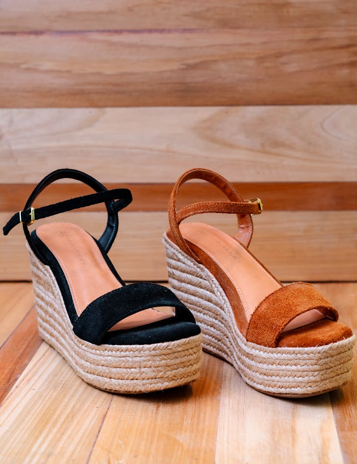 creative Pair of fashionable wedge sandals with rope espadrille soles displayed indoors on wooden flooring.