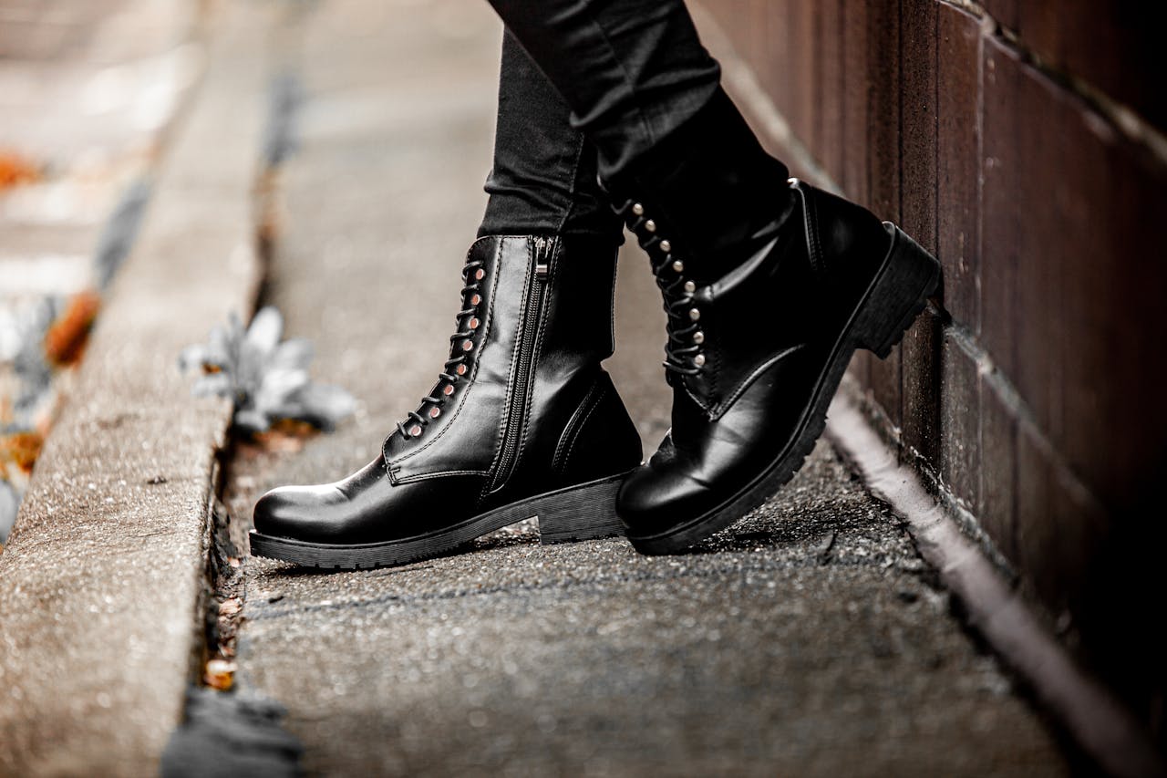 digital Black leather boots worn on a street sidewalk, displaying edgy fashion style.